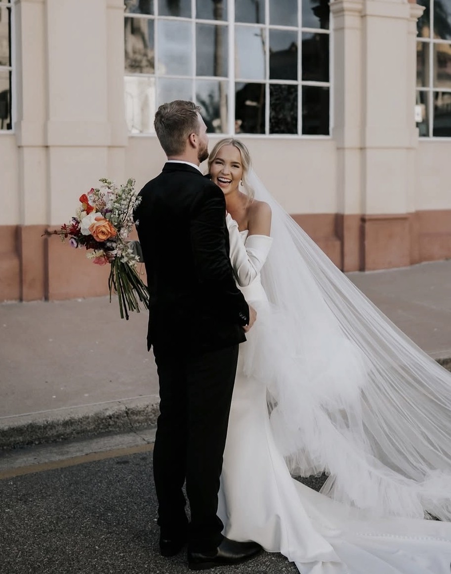 Bride and groom kissing under a floral arch